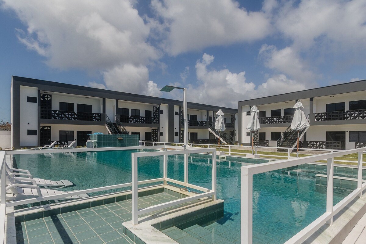 Ett modernt hotell med en swimmingpool, utomhusplats och en klar, blå himmel.