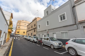 Una calle estrecha bordeada de vehículos estacionados y edificios.