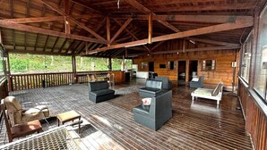Una terraza cubierta al aire libre con piso de madera, zonas de estar y grandes ventanales.