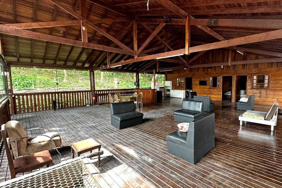 Una terraza cubierta al aire libre con piso de madera, zonas de estar y grandes ventanales.