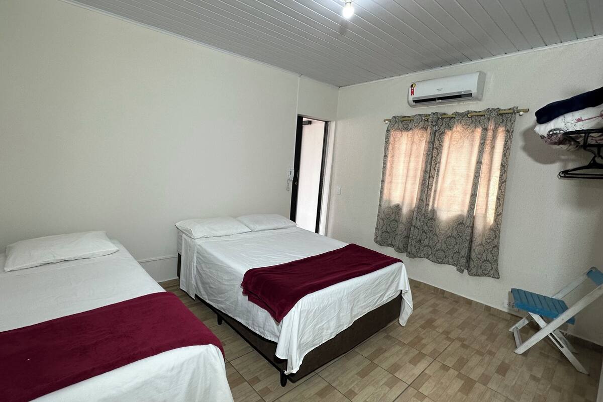 Una habitación con dos camas, un armario, aire acondicionado y una ventana con cortinas.
