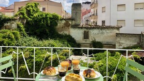 Un balcon avec une table préparée pour le petit-déjeuner, comprenant des croissants, un muffin et un verre de jus d’orange.