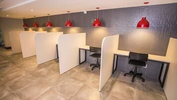 A modern office space with cubicles, red pendant lights, and a grey-tiled wall.