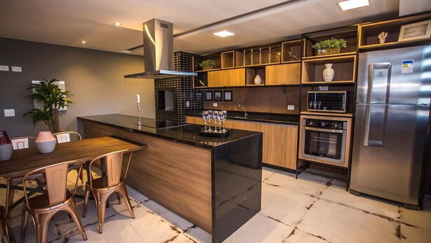 A modern kitchen with a central island, wooden cabinets, stainless steel appliances, and a built-in oven. - Studio com Sacada All You Need ALL0305 (Curitiba)