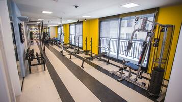 Un gimnasio con equipo de ejercicio, espejos y una pared amarilla.