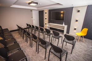 A conference room with rows of chairs, a large flat-screen TV, and a small white table with a vase. - Studio com Sacada All You Need ALL0305 (Curitiba)