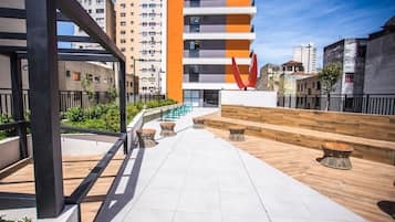 Een modern buitengebied met een houten terras, zitplaatsen en uitzicht op omliggende gebouwen.