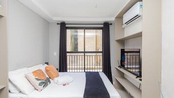 Una habitación de hotel con cama, televisión y balcón con barandilla.
