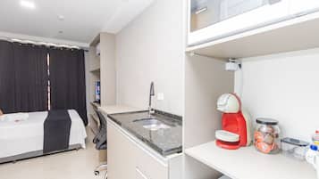 Une chambre d’hôtel équipée d’un lit, d’une petite kitchenette, d’une machine à café et d’un bocal de collations.