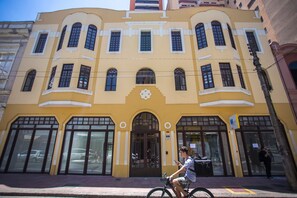 A yellow building with large arched windows and a central entrance. - Studio com Sacada All You Need ALL0305 (Curitiba)