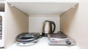 Une cuisine équipée d’une machine à café, d’une bouilloire et d’un cuiseur à riz, le tout posé sur un plan de travail blanc.