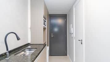 A narrow hallway with a kitchen area on the left, including a sink and countertop. A door is visible at the end of the hallway.