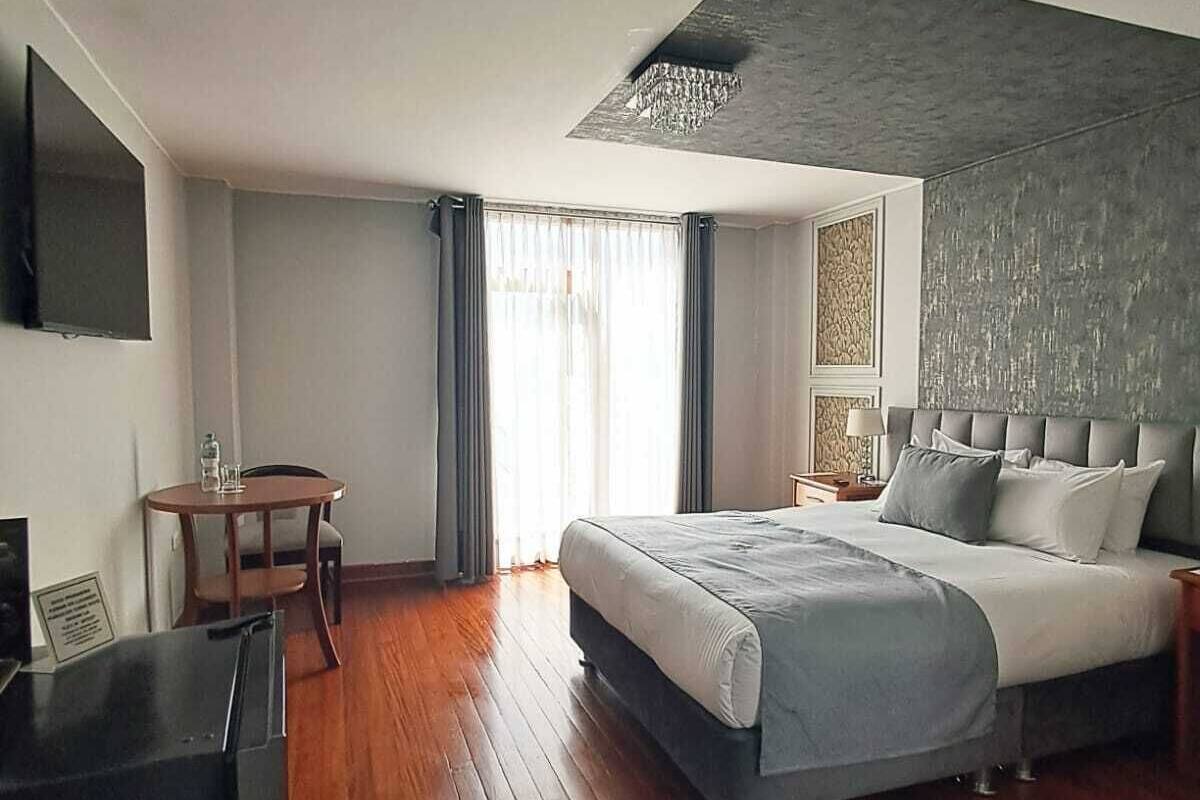 Una habitación de hotel moderna con una cama grande, un escritorio y un televisor.