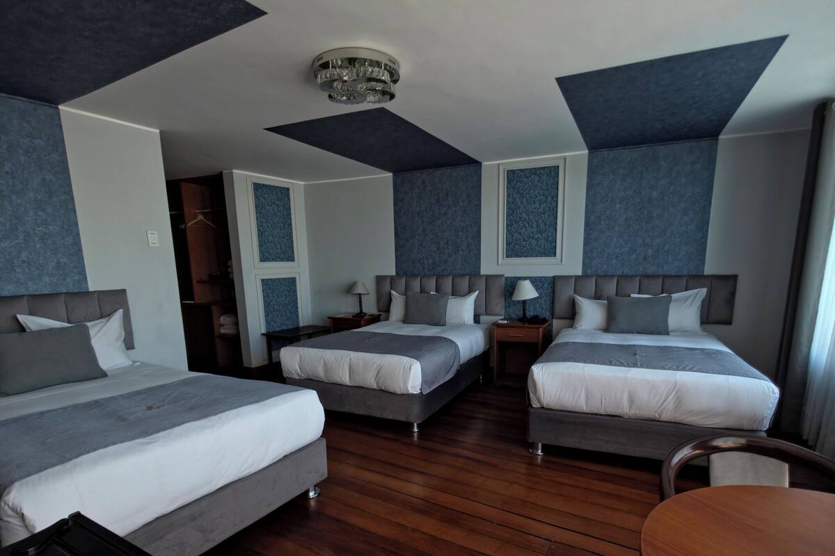 Una habitación de hotel con dos camas, una mesa de comedor y un armario.