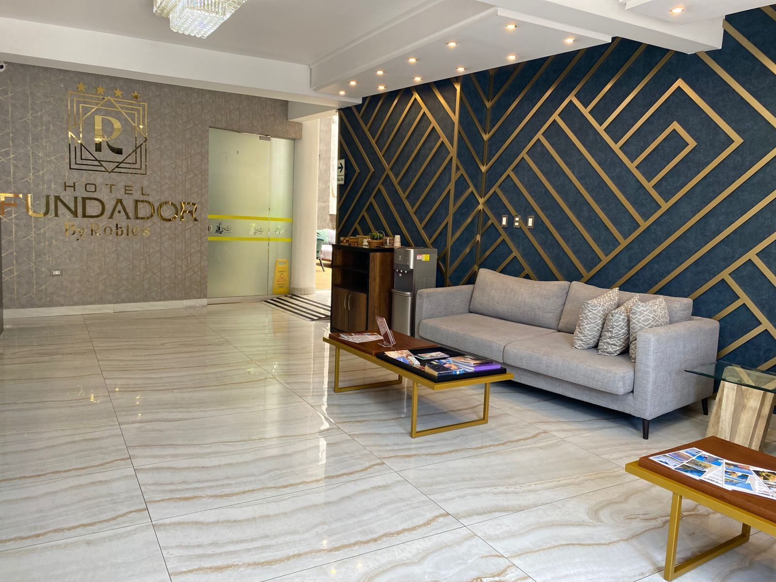 A hotel lobby with a modern design, featuring a reception desk, a sofa, and a coffee table.