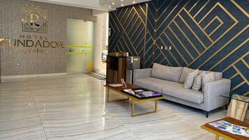 A hotel lobby with a modern design, featuring a reception desk, a sofa, and a coffee table.