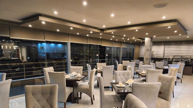 A modern dining area with tables and chairs, large windows, and a city view. - Hotel Fundador By Robles (Arequipa)