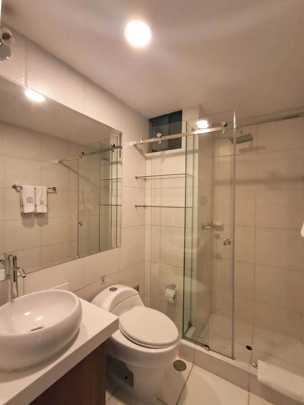 Een moderne badkamer met een douchecabine van glas, een wastafel met twee kommen en een toilet.