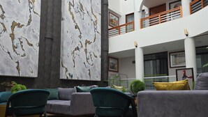 A spacious indoor area with modern furniture, a large abstract wall, and a multi-level balcony with railings. - Hotel Fundador By Robles (Arequipa)