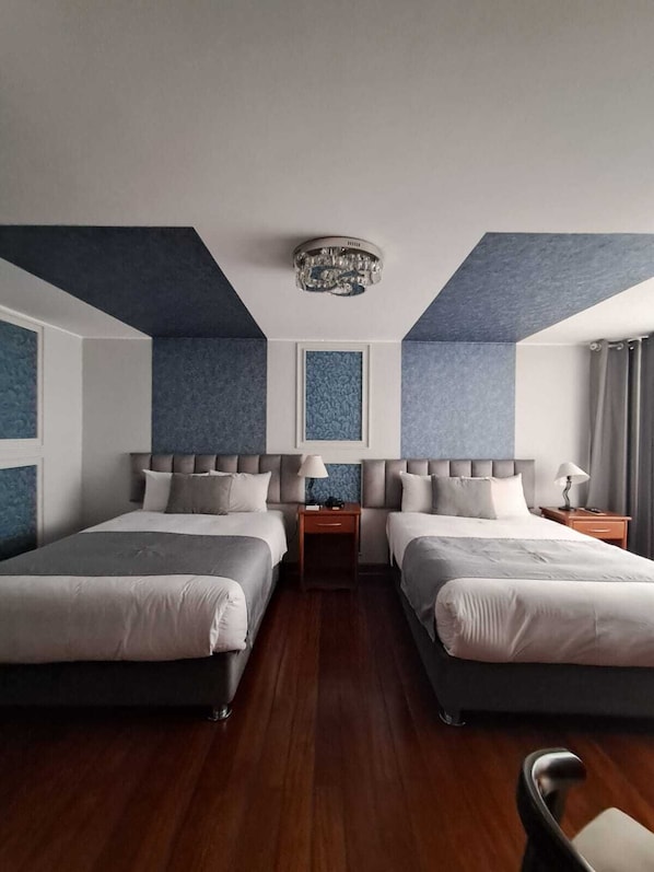 A hotel room with two beds, wooden flooring, and a modern ceiling light fixture. - Hotel Fundador By Robles (Arequipa)