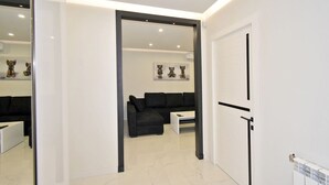 A modern living room with a black sofa, a white coffee table, and artwork on the wall. - Apartment by Luxe Group SA222 (Yerevan)
