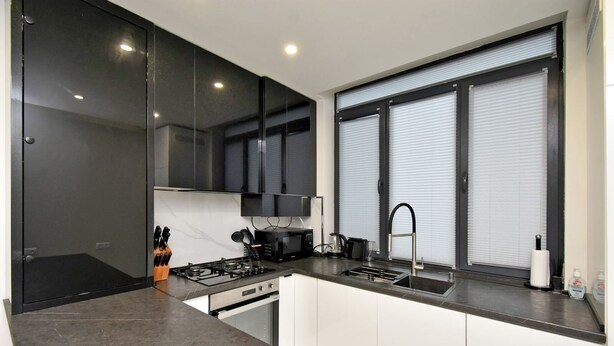 A modern kitchen with a gas stove, sink, and black cabinets. - Apartment by Luxe Group SA222 (Yerevan)