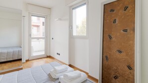 A hotel room with a bed, a door with a unique pattern, a window, and a view of the outside. - GuestHost - Bright Apartment M1 Precotto Milano (Milan)