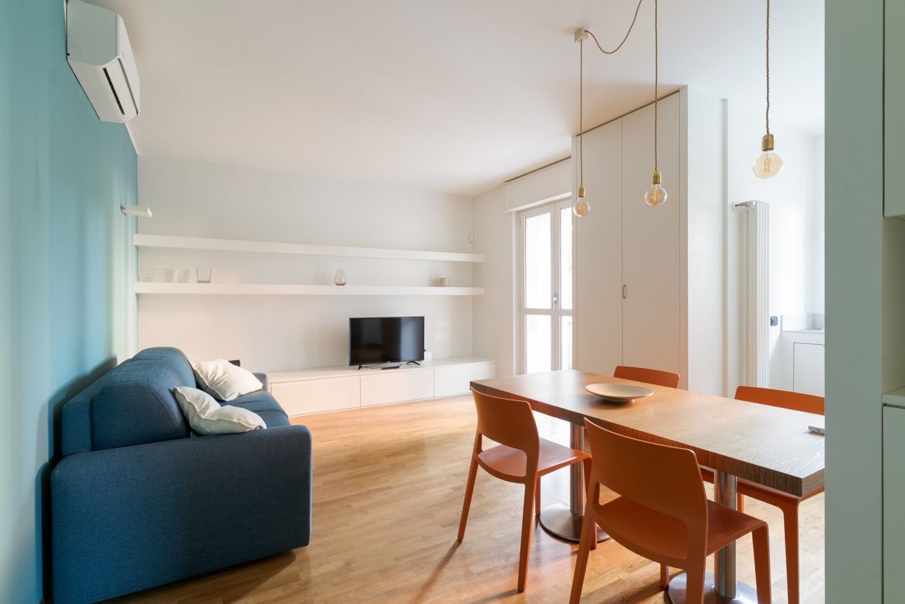 Un salon moderne comprenant un canapé, une table à manger avec des chaises, un téléviseur et un coin cuisine.