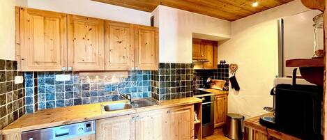 Una cocina con armarios de madera, salpicadero de azulejos y lavavajillas integrado.