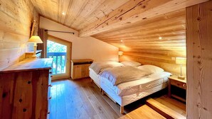 Quarto de cabana de madeira com cama, mesas de cabeceira e uma janela.