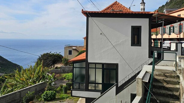 Un edificio moderno con techo de tejas rojas, una ventana pequeña y una escalera que lleva a un balcón.