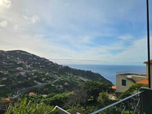 Un village côtier avec des maisons construites sur une colline, une route menant à la mer et une vue dégagée sur l’océan.
