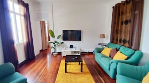 Un salon avec un canapé, une table basse, un téléviseur et une plante.