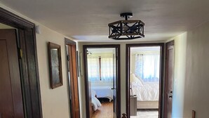 Un pasillo con suelo de madera que conduce a un dormitorio con cama y ventana.