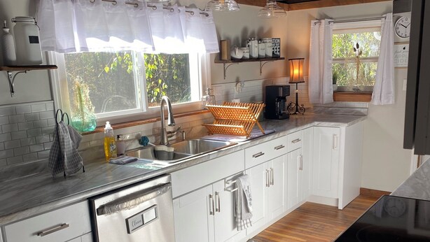 Una cocina moderna con armarios blancos, un lavamanos de acero inoxidable y techo de madera.
