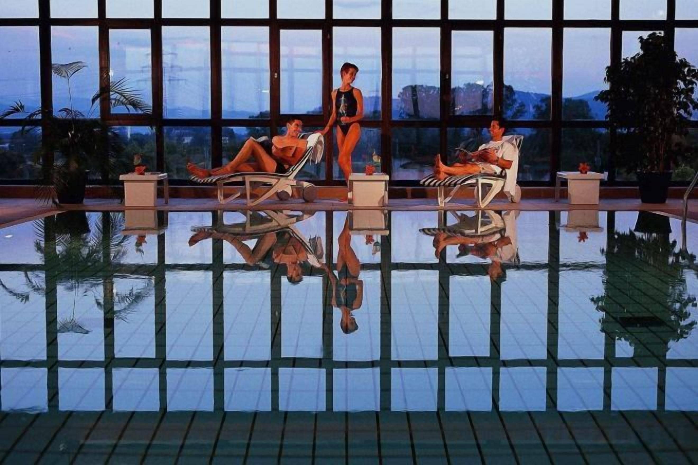 A pool area with lounge chairs and a person walking.