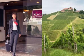 A person walking towards a hotel entrance with a sign for 'Mercury Acacia Hotel' and a view of vineyards in the background. - Mercure Hotel Offenburg am Messeplatz (Offenburg)