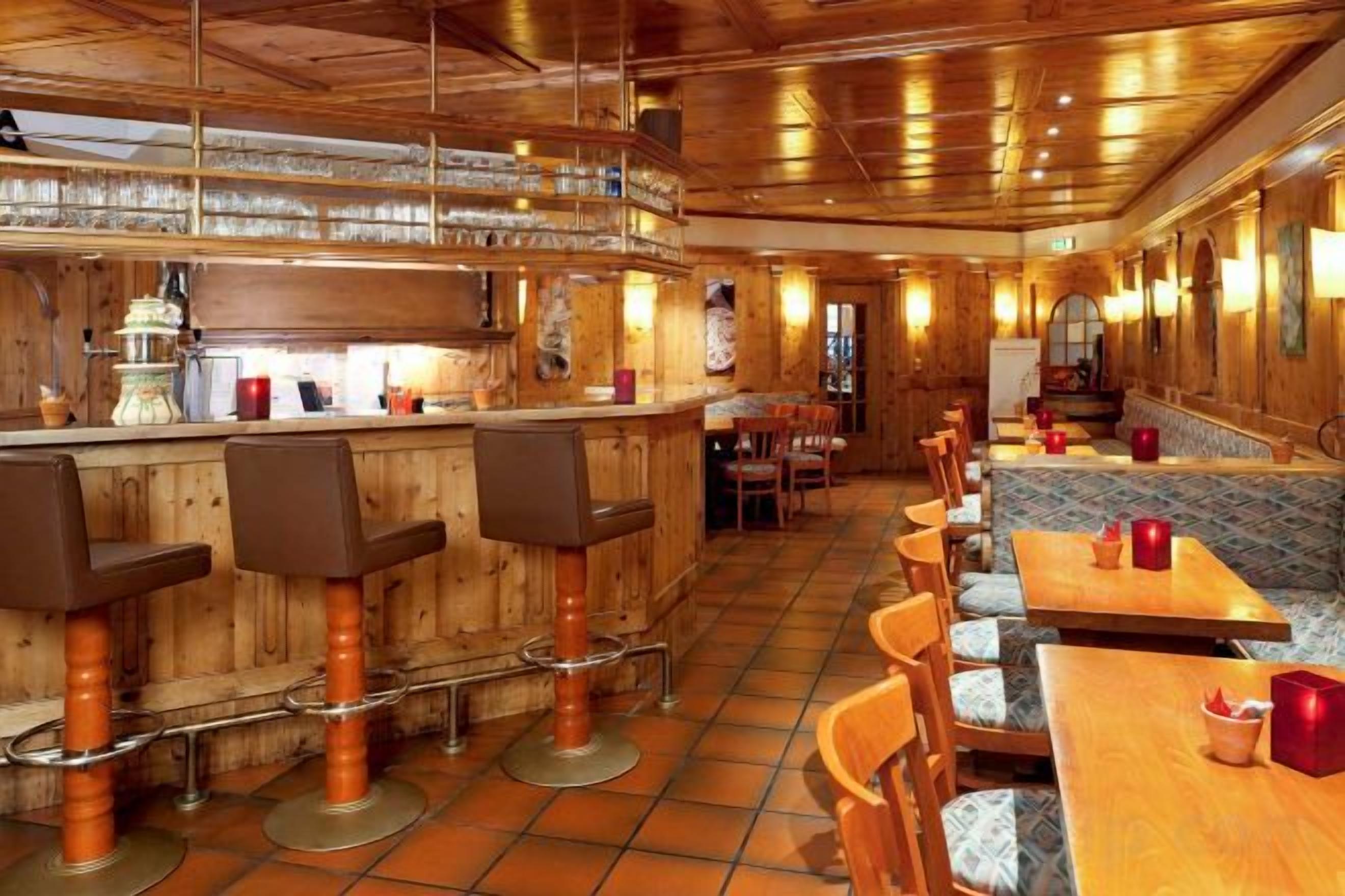 A bar area with stools, tables, and a counter.