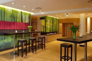 Un área de bar moderna con taburetes, una barra y un jarrón decorativo.