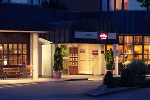A building with a storefront, a Christmas tree, and a bench outside.