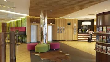 A reception area with a wooden ceiling, a reception desk, and a seating area with a unique sculpture.