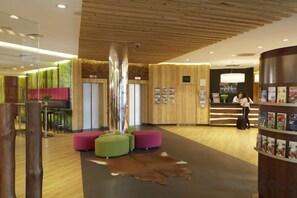 Un área de recepción con techo de madera, mostrador de recepción y un espacio de descanso con una escultura original.