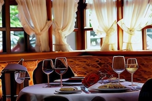 A dining table with wine glasses, plates of food, and a candle. - Mercure Hotel Offenburg am Messeplatz (Offenburg)