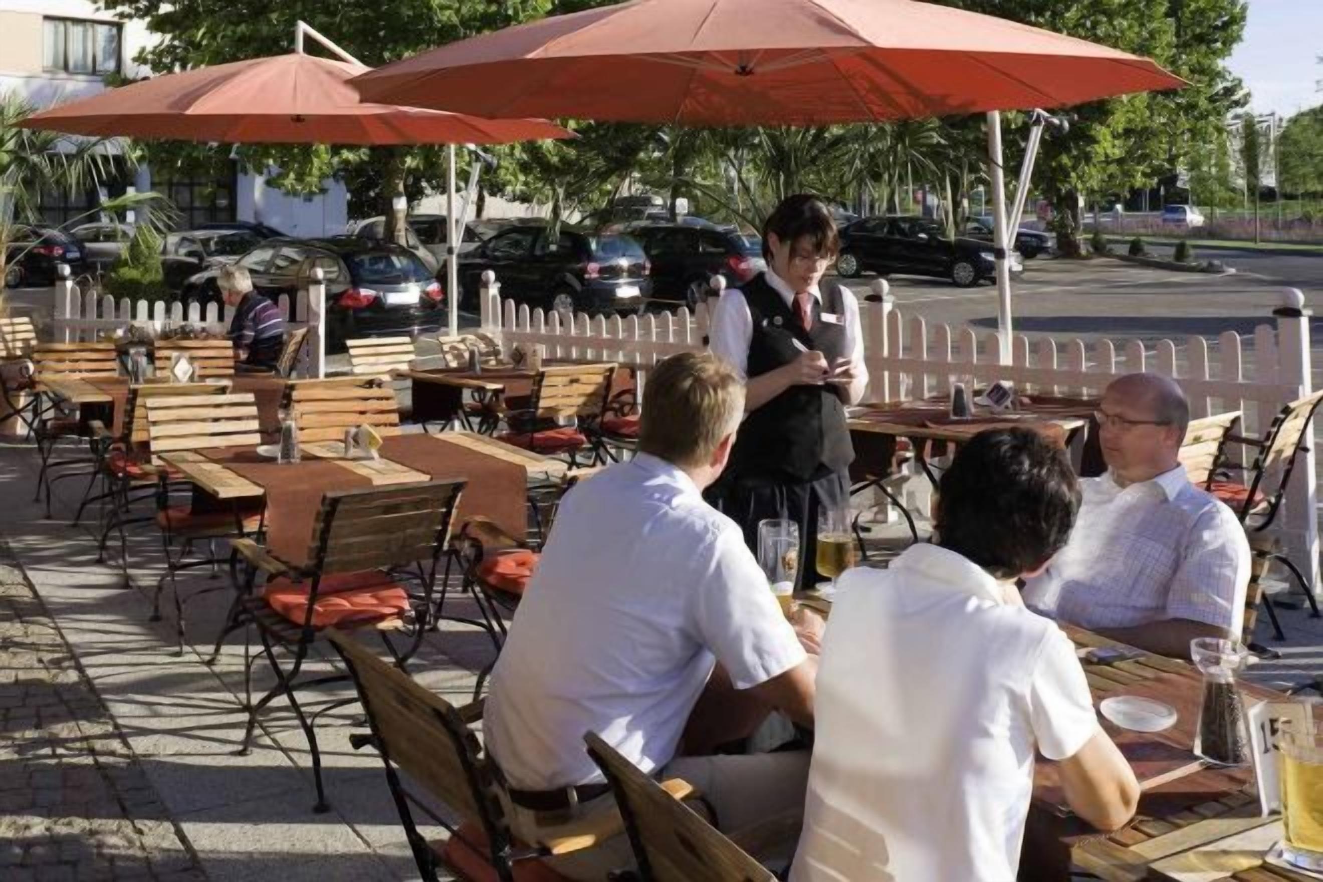 An outdoor café with tables and chairs, umbrellas, and a street view.