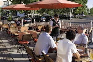 An outdoor café with tables and chairs, umbrellas, and a street view.