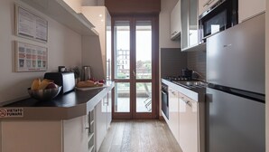 A modern kitchen with a stainless steel refrigerator, a stove, and a microwave. There is a window with a view of buildings outside. - Italianway Comfort - Gioia 59 (Milan)