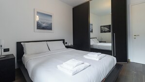 A modern hotel room with a large bed, a nightstand, a bedside table, a mirror, and a door. - Italianway Comfort - Gioia 59 (Milan)