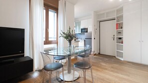 Eine moderne Küche mit weißen Schränken, einem Glastisch und Barhocker.