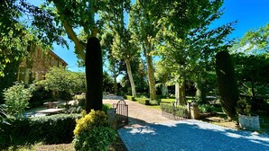 Un chemin de jardin qui mène à un bâtiment doté d’un mur en pierre et d’une porte en métal.