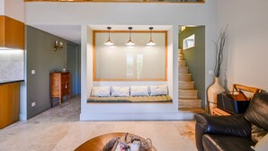 Un salon moderne avec un banc intégré, un escalier et un canapé en cuir.